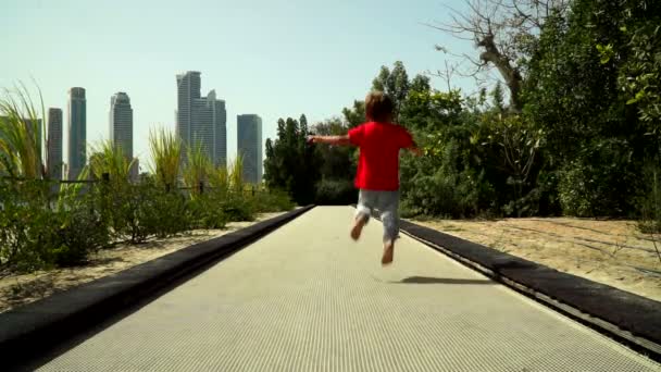 滑稽的小男孩与妈妈奔跑和跳跃在蹦床轨道在公园 努尔岛 蝴蝶花园 — 图库视频影像