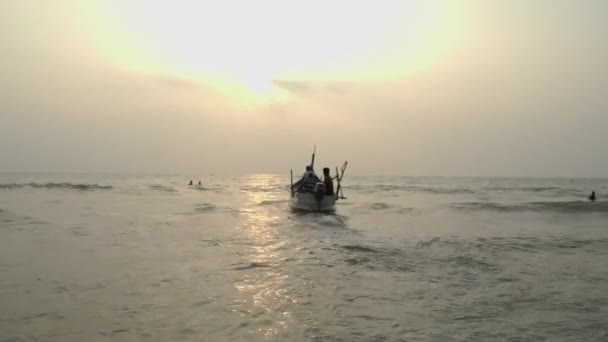 Arambol, Goa, India - 30 de diciembre de 2019: Los pescadores indios navegan en un barco en el mar al atardecer.. — Vídeos de Stock