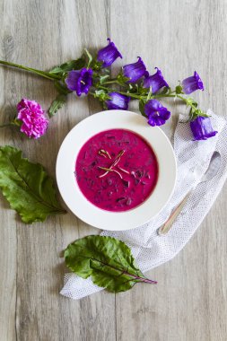 Pancar, pancar çorbası bırakır. Beyaz tabak, ahşap arka plan, çiçekler.