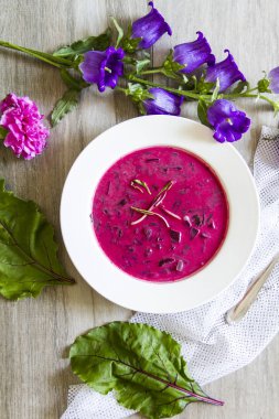 Pancar, pancar çorbası bırakır. Beyaz tabak, ahşap arka plan, çiçekler.