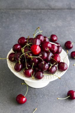Taze, tatlı kiraz beyaz tabakta Plato. Gri arka planı.