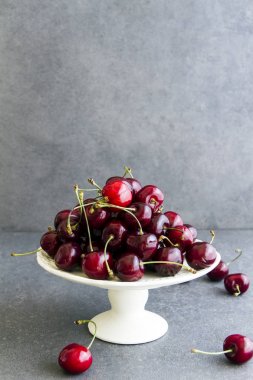 Taze, tatlı kiraz beyaz tabakta Plato. Gri arka planı.