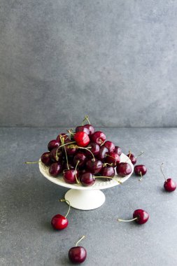Taze, tatlı kiraz beyaz tabakta Plato. Gri arka planı.