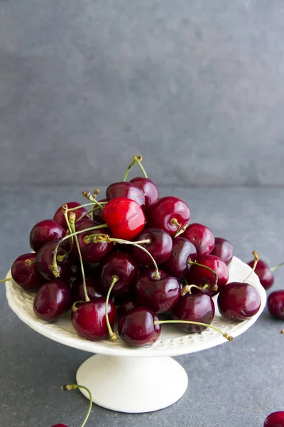 Taze, tatlı kiraz beyaz tabakta Plato. Gri arka planı.