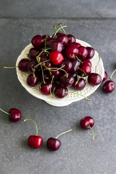 Taze, tatlı kiraz beyaz tabakta Plato. Gri arka planı.