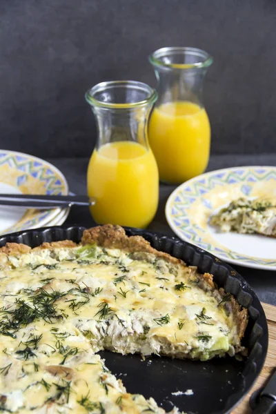 Füme uskumru ve pırasa tart veya kiş. Şişe suyu, gri arka plan, sarı ve mavi plakalı.