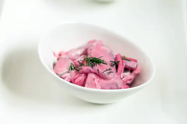 Ringa balığı salatası beetroots, elma ve soğan. Beyaz tabaklar, beyaz artalanları. İzole.