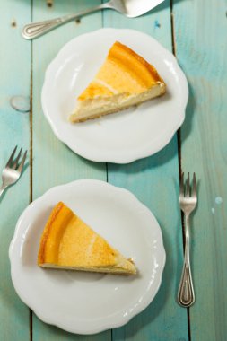 Kavrulmuş tereyağı ile peynirli kek. Mavi ahşap masa, beyaz tabaklar.