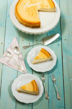 Kavrulmuş tereyağı ile peynirli kek. Mavi ahşap masa, beyaz tabaklar.