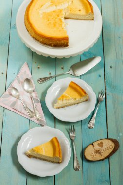 Kavrulmuş tereyağı ile peynirli kek. Mavi ahşap masa, beyaz tabaklar.