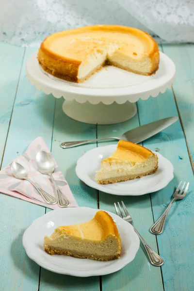 Kavrulmuş tereyağı ile peynirli kek. Mavi ahşap masa, beyaz tabaklar.