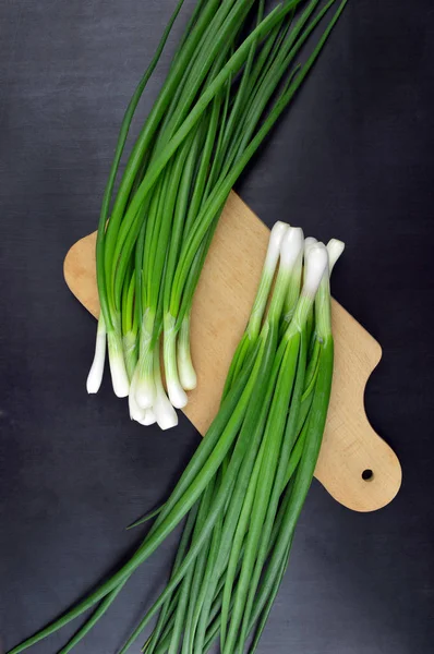 Cebollas verdes frescas en una tabla de corte.Vista superior . —  Fotos de Stock