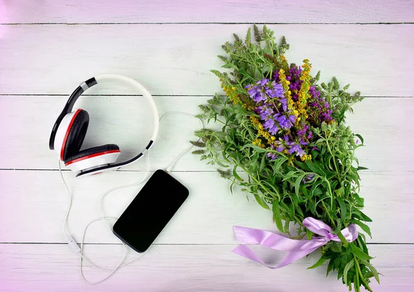 Smartphone, headphones and flowers on wooden background. Top vie