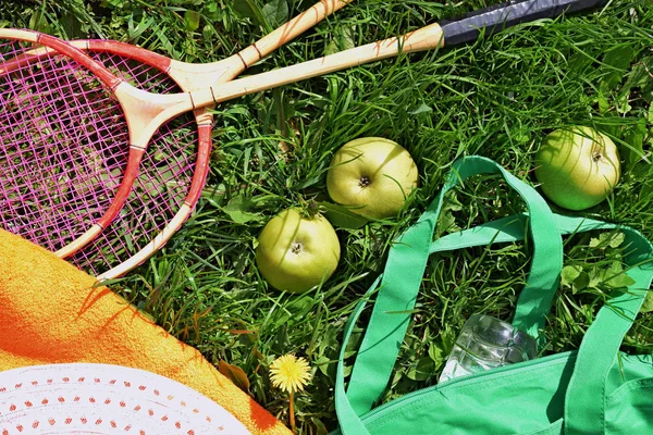 Badminton, chapeau, serviette, raquettes et pommes sur l'herbe verte . — Photo