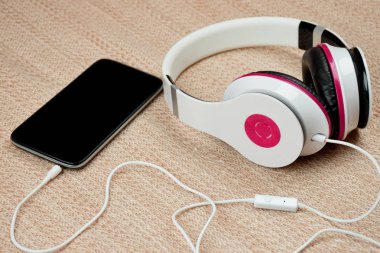 Smartphone and headphones on the tissue background / close-up /.