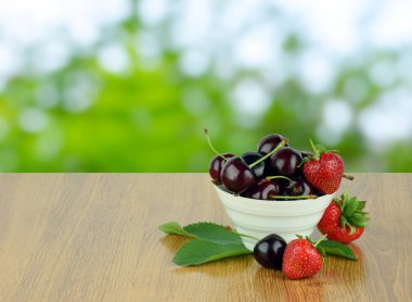 Olgun Kiraz ve çilek yaprakları bir kase ile.