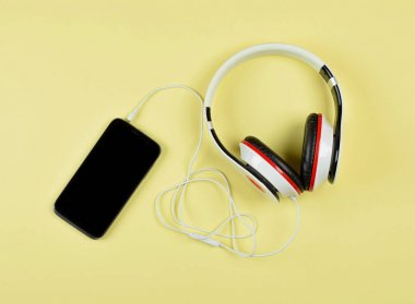 akıllı telefon ve kulaklık üzerinde sarı bir arka plan.