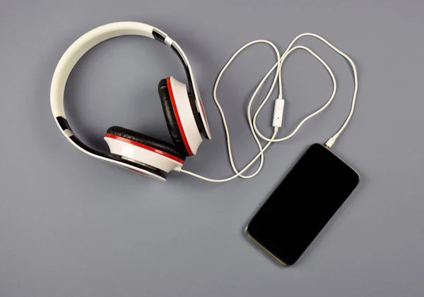 Smartphone e fones de ouvido em um fundo cinza . — Fotografia de Stock