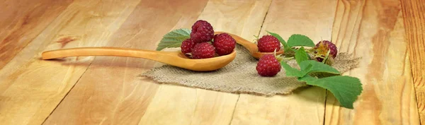 Raspberry with leaves on a wooden background. Rural atmosphere.
