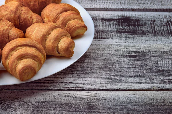 Fresh croissants on a white plate, close-up. Breakfast. — Stock Photo, Image