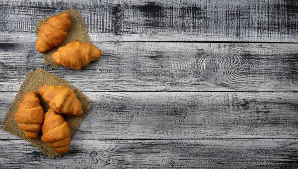 Fresh croissants on an old wooden table. Top view. — Stock Photo, Image