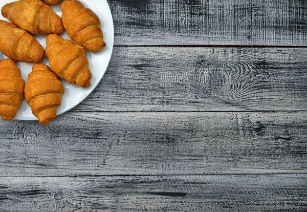 Fresh croissants on an old wooden table. Top view. — Stock Photo, Image