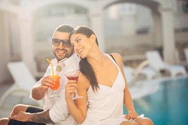Kokteyller havuz kenarında yaz tatile sahip Youbg sevgi dolu çift. Romantik akşam lüks Resort. Aşk, nişan, yıldönümü kutlama. Birlikte vaktinizi. Yarın ile rahatlatıcı