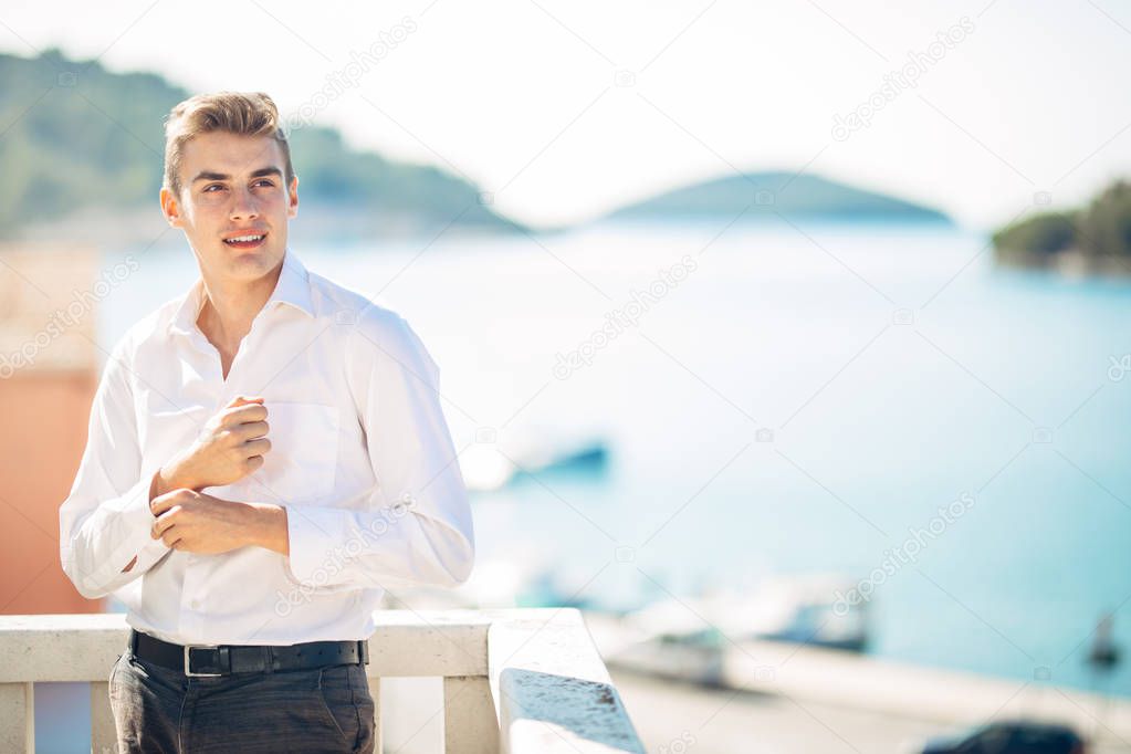 Young handsome man enjoying stay at luxury resort hotel with panoramic view on the sea.Smiling cheerful business man at a earned tropical vacation.Summer vacation traveling.Cruise