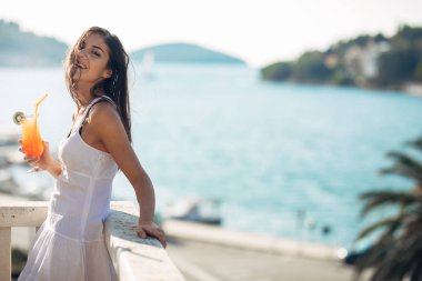 Güneşli bir günde eğleniyor, okyanus manzarası ile rahatlatıcı, dalgaları dinleyerek, serinletici içecek ile yaz zevk tatil yaz tatili kaygısız genç kadın. Yaz aşkı. Hak ettiği tatil