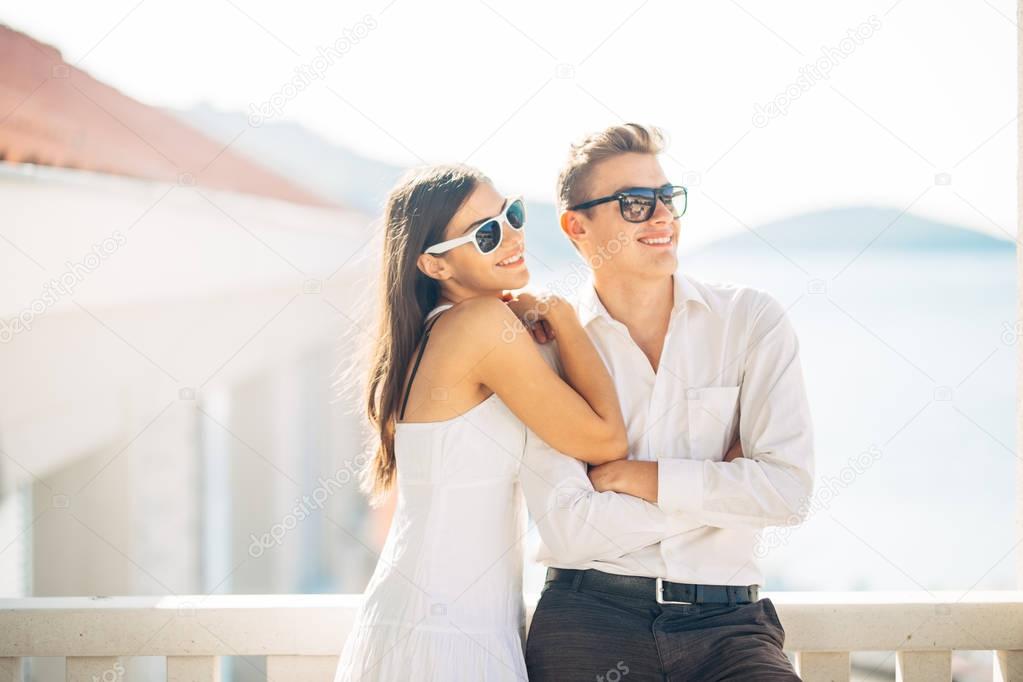 Attractive couple looking at amazing sea view.Enjoying sun and sunny weather and breathing in fresh ocean air.Enjoying moment outside.Two people sharing precious moment together.Happiness and leisure