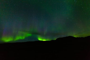 Etkileyici yeşil Aurora Borealis (Kuzey ışıkları) Iceland.Northern Kutbu fenomen. Kuzey Kutup dairesi dağlar üzerinde doğal ışık gösterisi. Kutup görünür ışık, Manyetik Parçacık çarpışma görüntüleme