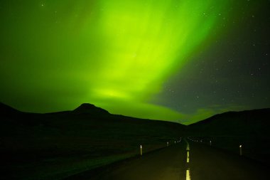 Impressive green Aurora Borealis (Northern lights) in Iceland.Northern pole phenomenon.Natural light show above arctic circle mountains.Visible polar light,magnetic particle collision display clipart