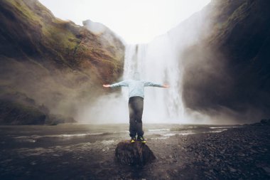 Turist Iceland.Man güçlü doğa ile karşılaştırıldığında güneyinde meşhur Skogafoss Şelalesi önünde duruyor. Küçük insan doğa kavram. İnsan ve doğa bağlantı kavramı. Seyahat, kamp, keşfetmek