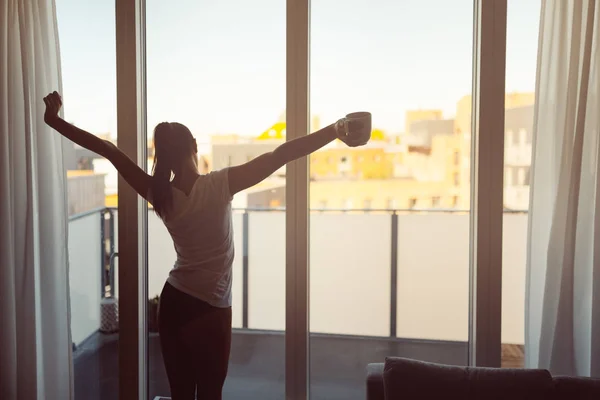 Sleepy woman stretching,drinking a coffee to wake up early in the monday morning sunrise.Starting your day.Wellbeing.Positive energy,productivity,happiness,enjoyment concept.Morning ritual