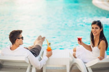 Olumlu mutlu çift rahatlatıcı lüks yaz tatil tatil havuzun yanında. Kokteyl içme. Spa Sağlık Merkezi birlikte vaktinizi. Yaz aylarında gevşeme. Seyahat, balayı konsepti pampering,