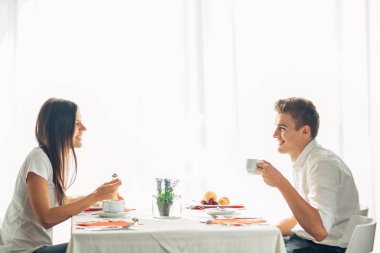 Mutlu çift restoranda öğle yemeği yemek. Yemek üzerine söz. Otel tam pansiyon, her şey dahil konaklama. Seyahat, Tarih, gıda, yaşam tarzı. Gülümseyen insanlar sağlıklı kahvaltı yapıyor. Gıda inceleme. Masada görgü