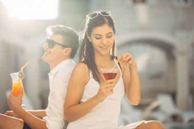 Havuz yaz tatil tatil kokteyller sahip iki çekici insan. Havuz lounge bar partisi. Zevk serinletici içecekler ve günün dinlenmek egzotik seyahat etmek tatil üzerinde bir çift gördüm. Arkadaşlar eğlenmeye