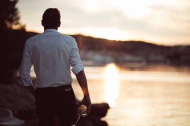 Genç iş adamı yalnız şarap içme vurguladı. Alkollü adam alkol bağımlısı yaşamı ile mutsuz. İçki alemi. Elinde bir içkiyle yalnız. İş kaybetme. Alkol bağımlılığı kavramı.