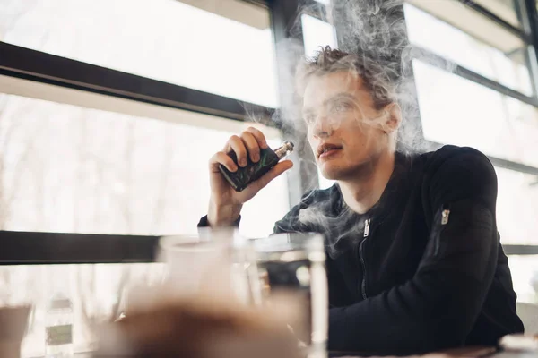 年轻人在封闭的公共空间 Vaping 在咖啡馆里吸烟的电子香烟 尼古丁成瘾 戒烟的方法 老习惯 Vaping 城市男子使用电子香烟的地方吸烟是不允许的 — 图库照片