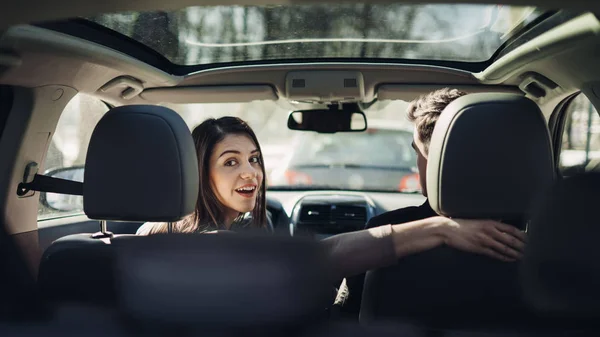 Young woman in a car,female driver looking at the passenger and smiling.Enjoying the ride,traveling,road trip concept.Driver feeling happy and safe.Learning how to drive,getting drivers licence.