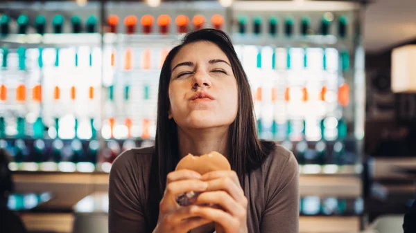 Genç kadın yemek yağ hamburger. Özlem lokanta. Abur cubur yeme suçlu zevk zevk. Memnun ifade. Son dakika diyet kuralları, diyet kadar vererek. Sağlıksız dengesiz beslenme kalori alımını.
