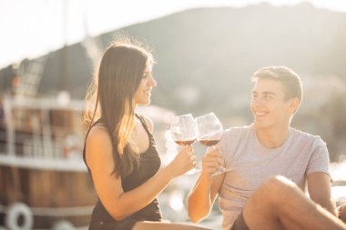 Romantik bir çift gün batımında şarap içiyor. Romantik bir akşam. İki kişi deniz kenarında bir kadeh şarapla romantik bir akşam geçiriyor.