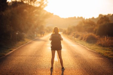 Genç, sırt çantalı, maceraperest bir kadın yolda otostop çekiyor. Hayat macerasına hazır. Seyahat tarzı. Düşük bütçeli seyahat.