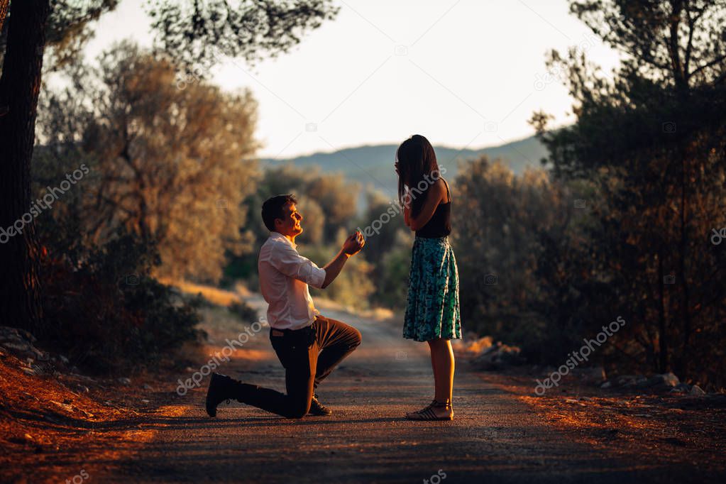 Man in love proposing a surprised,shocked woman to marry him.Proposal, engagement and wedding concept.Betrothal.Being affianced to love of life.Kneeling,getting down on knees.Ring offering.Marriage