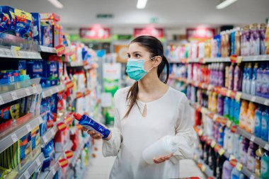 Virüs salgını için koruyucu maske takan kadın karantinaya alındı. Hijyen, temizlik ve dezenfeksiyon ürünleri. Engelleyici önlemler ve koruma. Salgın sırasında üst düzey alışveriş..
