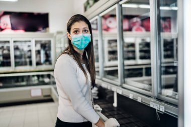 Maske takan ve eldiven takan bir kadın, marketten tükenmiş ürünlerle yiyecek / erzak alıyor. Coronavirus covid-19 salgını nedeniyle yiyecek stokları azaldı.