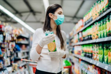 Doğal vitamin ve mineral kaynağı. Portakal suyu. Süpermarkette yüz maskesi takan C vitamini kadın. Patojen virüsü salgını için hazırlanan kadın.