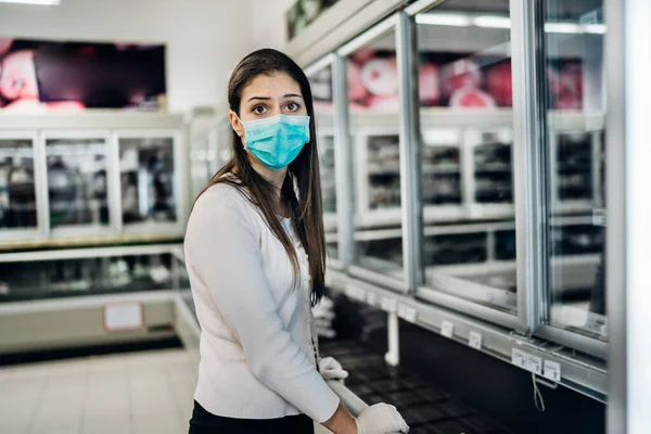 Maske takan ve eldiven takan bir kadın, marketten tükenmiş ürünlerle yiyecek / erzak alıyor. Coronavirus covid-19 salgını nedeniyle yiyecek stokları azaldı.