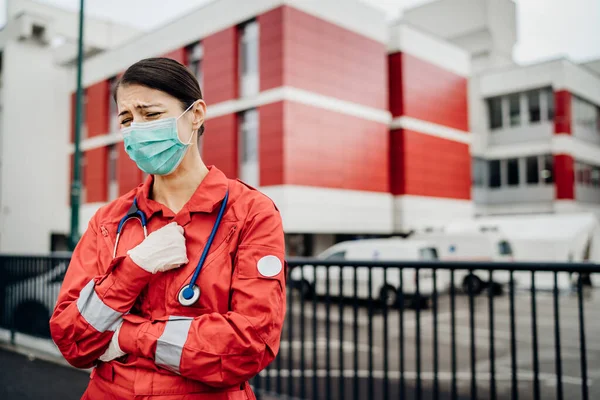 Crying paramedic in front of isolation hospital facility.Mental melt down of medical professional.Emergency room doctor in fear and stress,pressure of fight against corona virus.Covid-19 deaths impact