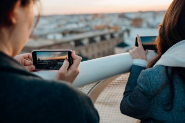 Akıllı telefonuyla fotoğraf çeken genç bir kadın, şehir manzarası açısından gün batımının tadını çıkarıyor. Sevilla, Endülüs, İspanya 'da inanılmaz deneyimi olan bir turist. Güneşin ve panoramın tadını çıkarıyor. Seyahat fotoğrafçılığı.